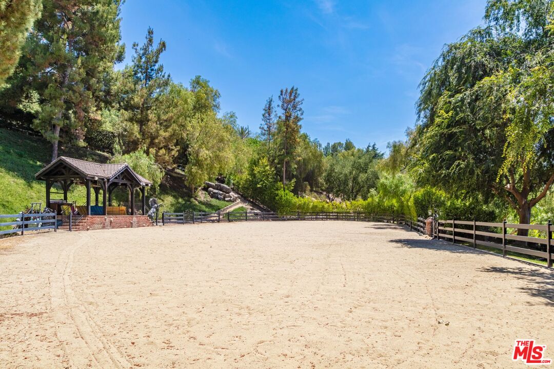 5841 Round Meadow Road Hidden Hills, CA 91302 - Photo 27 of 33 a backyard of a house with table and chairs under an umbrella