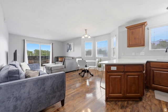 116 East Resaca Drive, Unit F6 Sandy, UT 84070 - Photo 10 of 32 Open-concept living area featuring wood-finish flooring, a kitchen island with a white countertop, and a dining area with a bay window