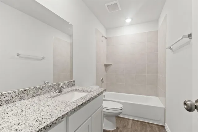 a bathroom with a granite countertop sink a toilet and shower