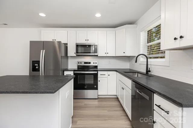 a kitchen with kitchen island granite countertop a sink stove and refrigerator