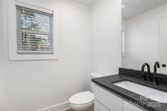 a bathroom with a granite countertop sink toilet and a mirror