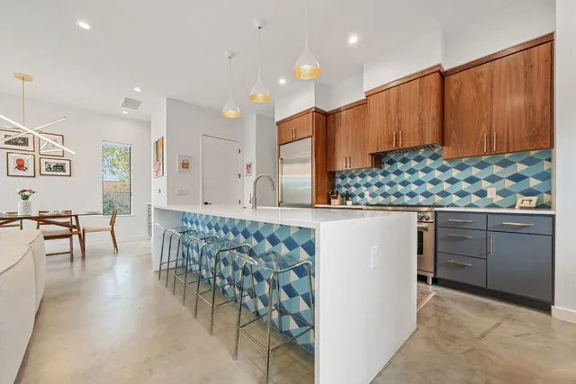 a kitchen with stainless steel appliances kitchen island granite countertop a stove a sink a dining table and chairs