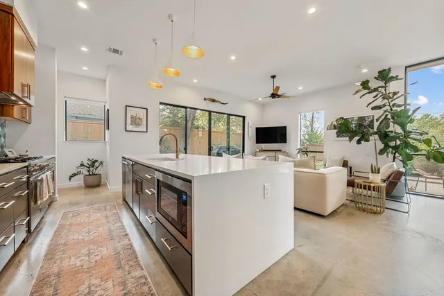 a kitchen with stainless steel appliances kitchen island granite countertop a stove a sink dishwasher and a flat screen tv