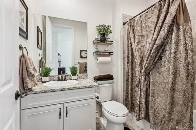 a bathroom with a granite countertop sink toilet and a mirror