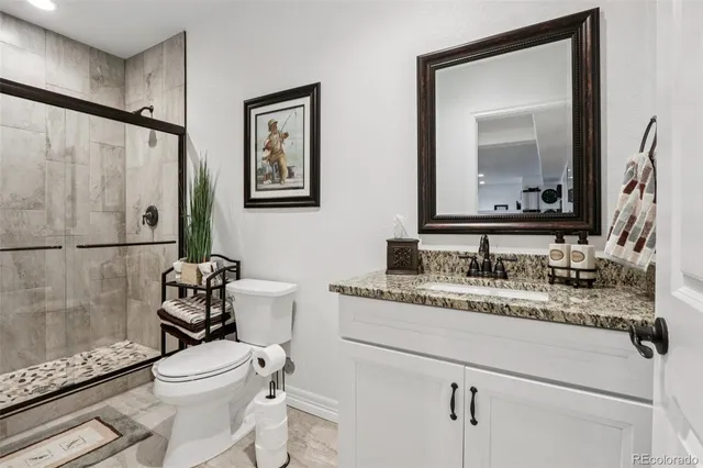 a bathroom with a granite countertop toilet sink and mirror