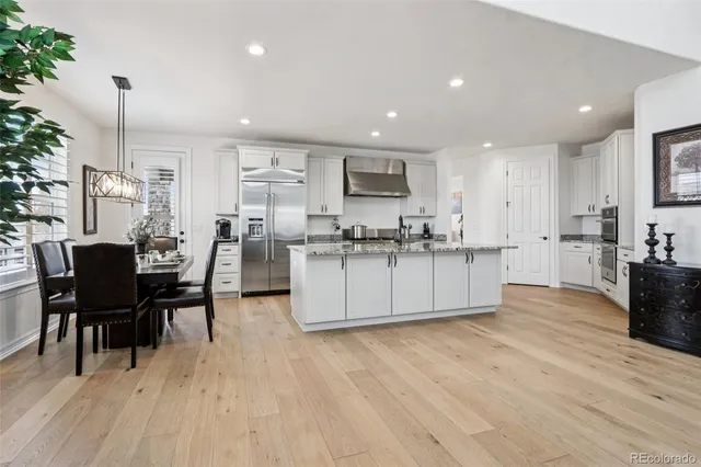 a kitchen with stainless steel appliances kitchen island granite countertop a table chairs and a refrigerator