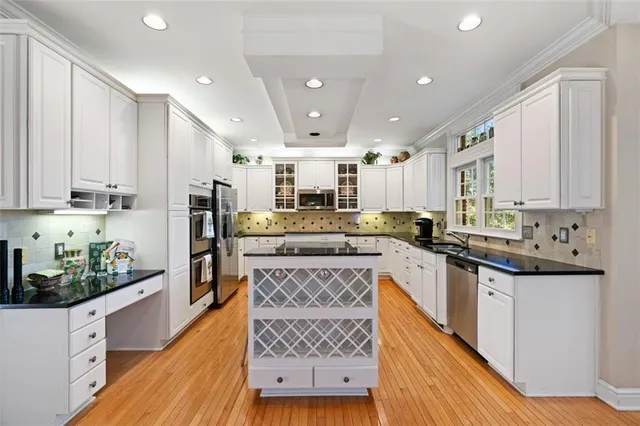 a kitchen with stainless steel appliances granite countertop a refrigerator a sink dishwasher and white cabinets with wooden floor