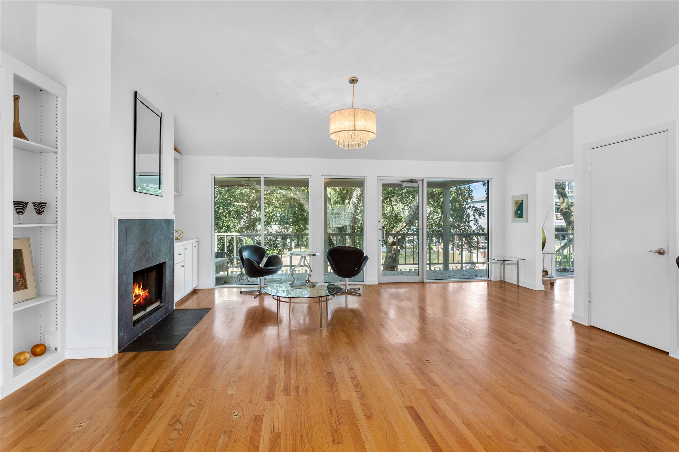 67 Harbor Lane Kemah, TX 77565 - Photo 6 of 47 This inviting living area boasts hardwood floors, a modern fireplace, and expansive glass windows and door opening to scenic waterfront views. Bright and airy, it features a chic chandelier and elegant built-in shelving.