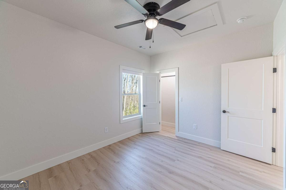 802 Mull Valley Road Morganton, GA 30560 - Photo 35 of 75 an empty room with wooden floor a ceiling fan and windows
