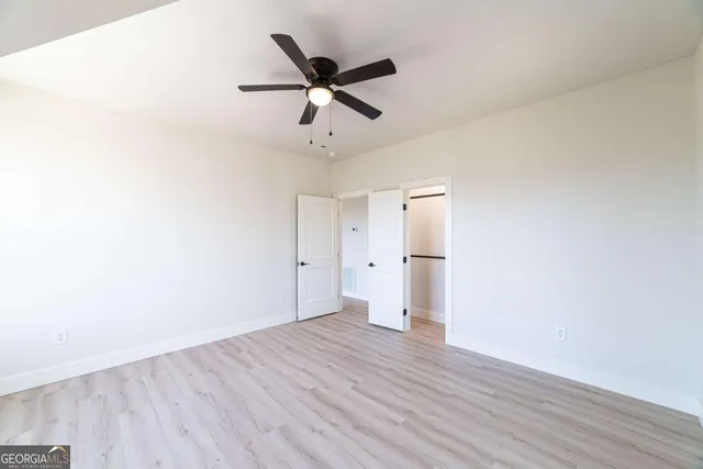 a view of empty room with wooden floor and fan