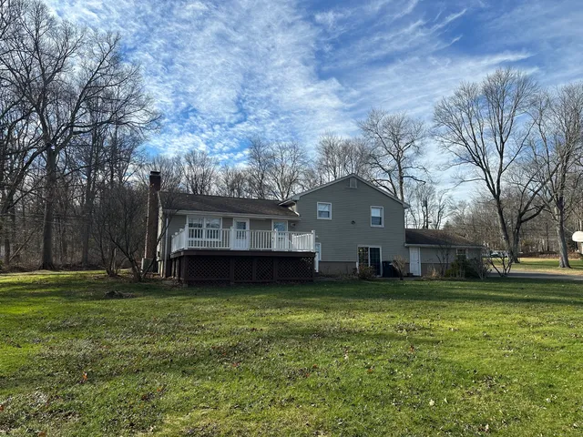 a view of a house with a big yard and large trees