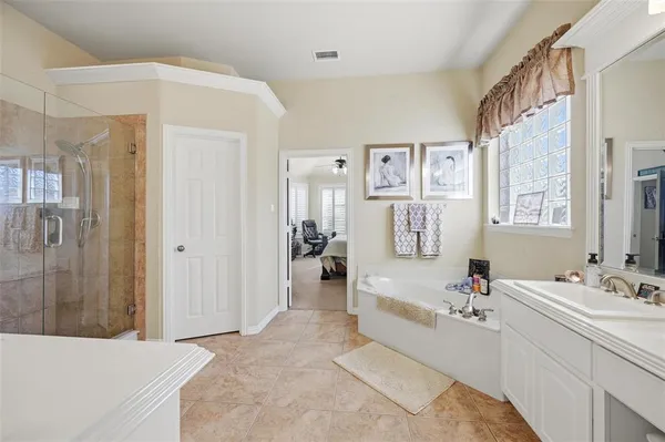 a bathroom with a tub sink double vanity and shower