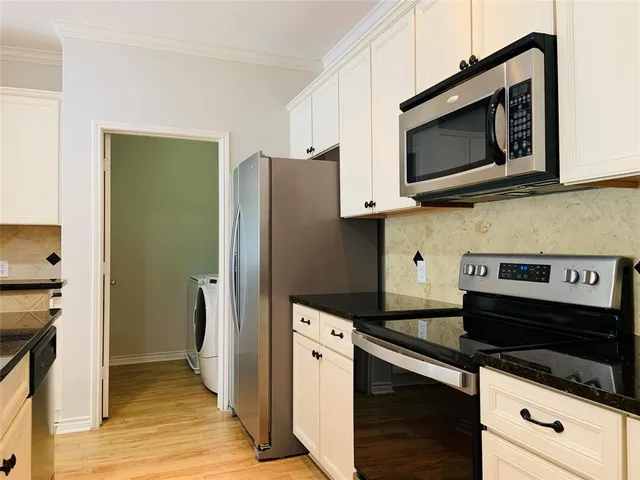 a kitchen with stainless steel appliances white cabinets and a stove top oven