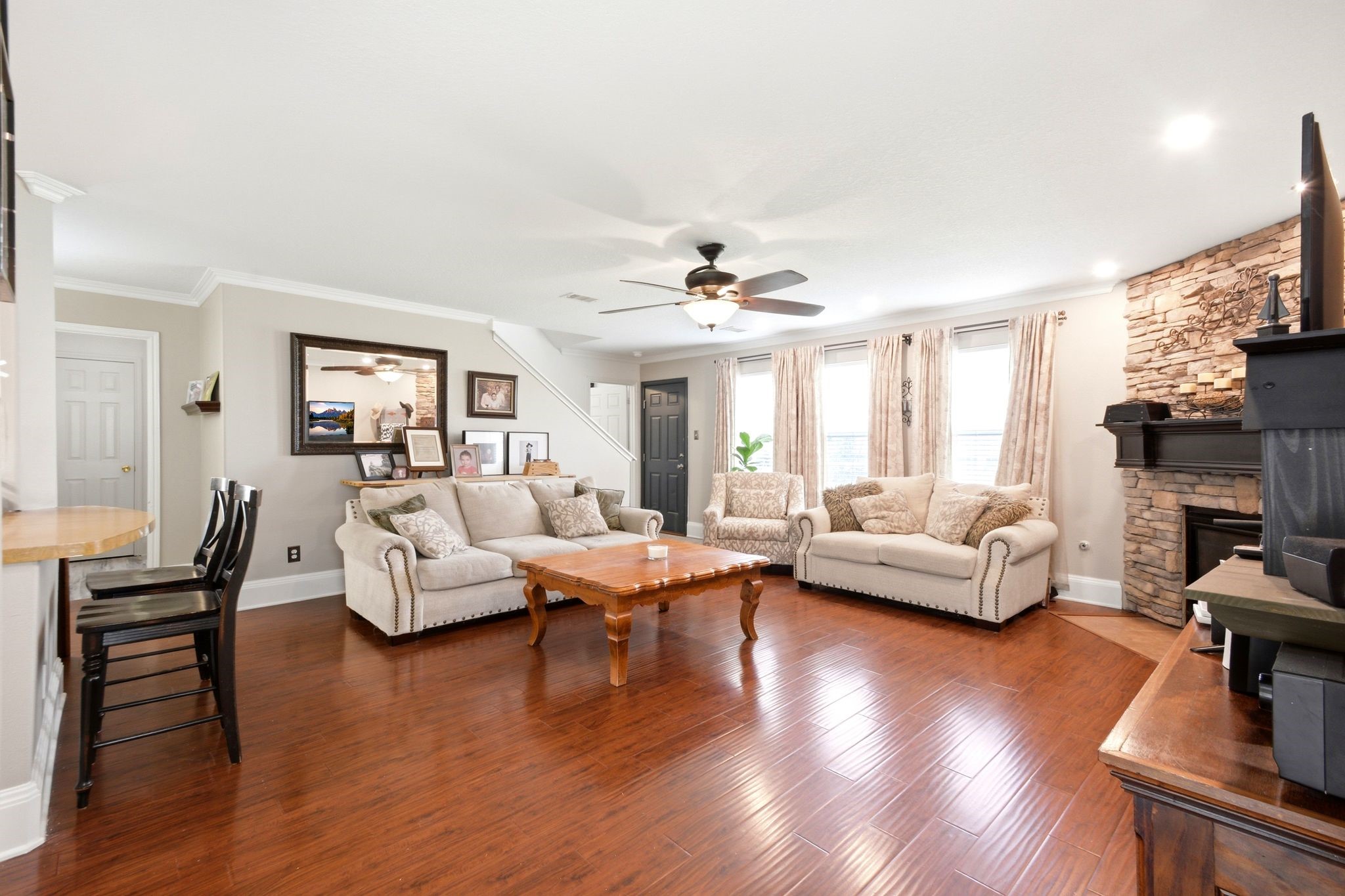 16954 Tableland Trail Conroe, TX 77385 - Photo 7 of 33 Warm and welcoming living room with hardwood floors, crown molding, abundant natural light, and a beautiful stone fireplace. The open-concept layout provides ample space for everyday living and entertaining.