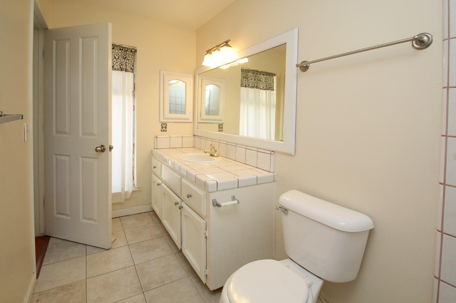 834 Fordham Avenue Clovis, CA 93611 - Photo 15 of 26 a bathroom with a granite countertop toilet sink and mirror