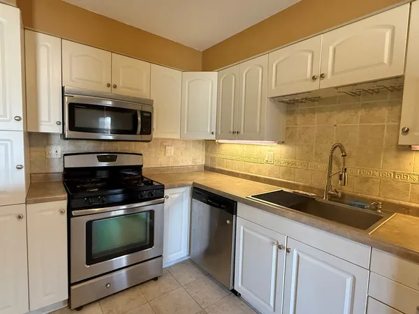 a kitchen with granite countertop a stove a sink and dishwasher a oven with wooden cabinets