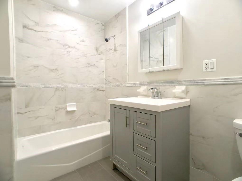 621 48th Street Brooklyn, NY 11220 - Photo 8 of 14 a bathroom with a sink mirror vanity and bathtub