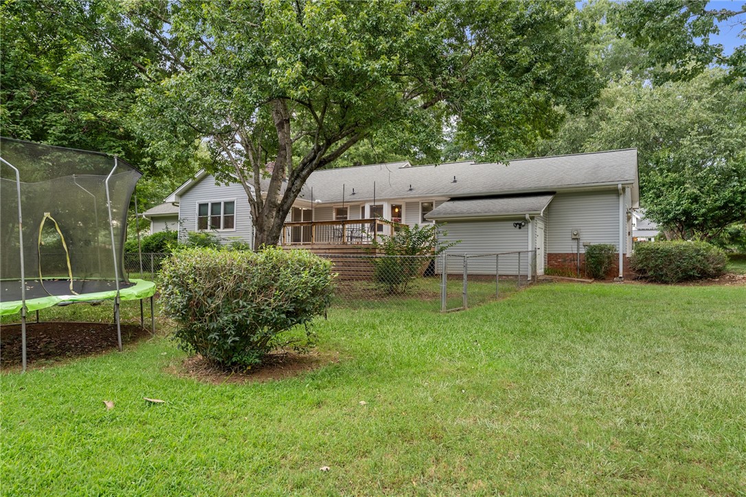 1014 East Queen Street Pendleton, SC 29670 - Photo 34 of 43 A spacious backyard with mature trees and a comfortable elevated deck, perfect for relaxation and outdoor activities.
