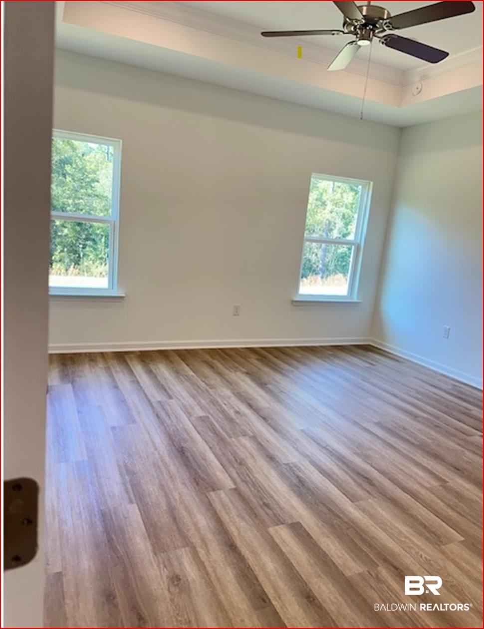 13906 Antler Hl Road Daphne, AL 36527 - Photo 6 of 23 Unfurnished room with a tray ceiling, ceiling fan, plenty of natural light, and light hardwood / wood-style floors