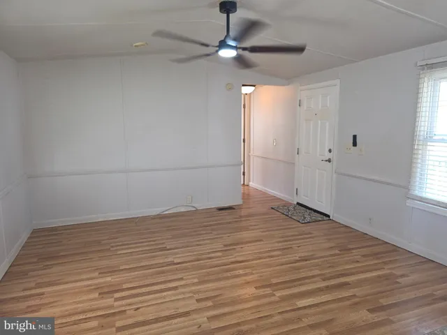 a view of empty room with wooden floor and fan