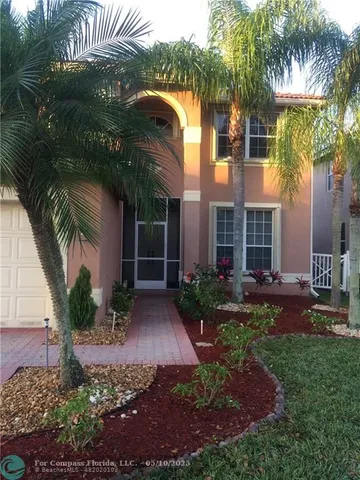 a view of a house with a yard and palm trees