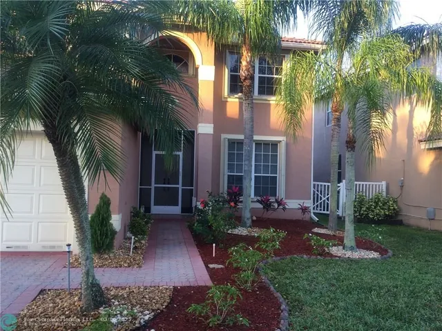 a view of a house with a yard and palm trees