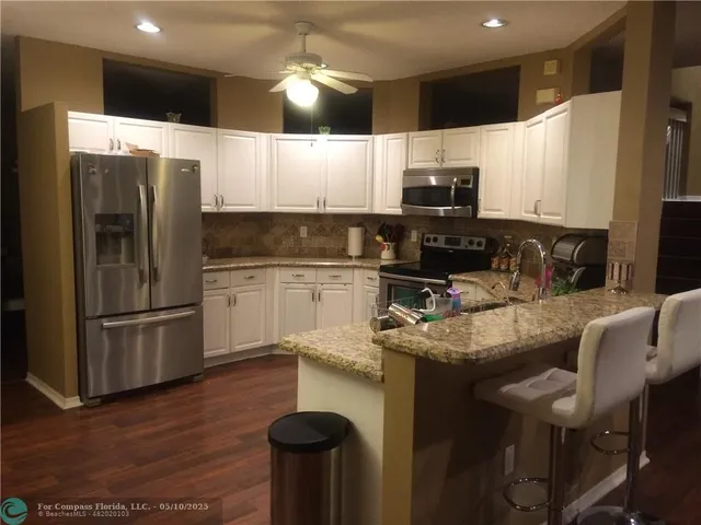 a kitchen with stainless steel appliances granite countertop a sink refrigerator and microwave