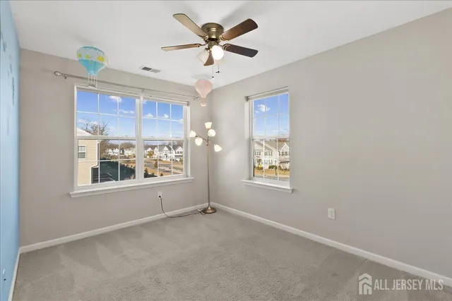 an empty room with windows and ceiling fan