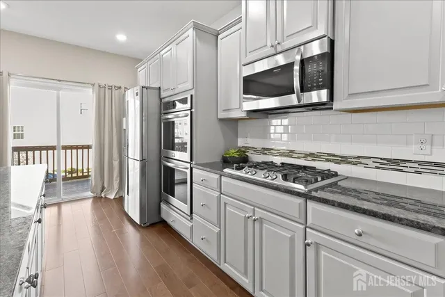 a kitchen with stainless steel appliances white cabinets and a stove top oven