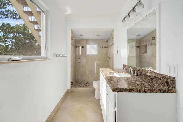 a bathroom with a granite countertop sink a mirror and a shower