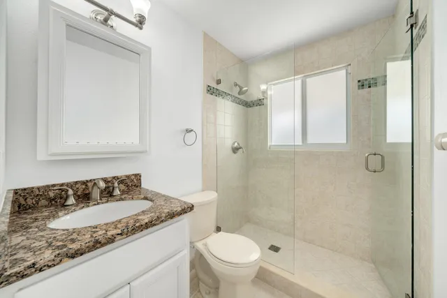 a bathroom with a granite countertop sink toilet and shower