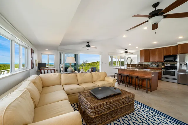 a living room with furniture kitchen view and a large window