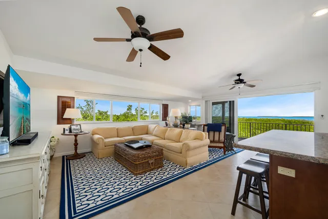 a living room with furniture a ceiling fan and a flat screen tv