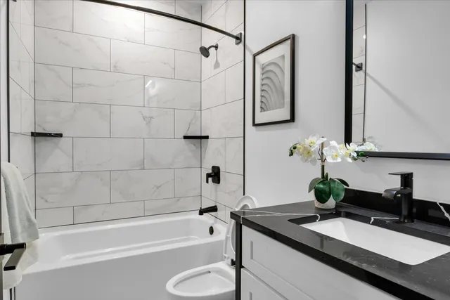 a bathroom with a granite countertop sink a toilet and bathtub