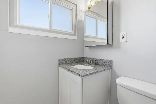 a bathroom with a granite countertop toilet sink and mirror