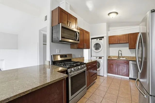 a kitchen with stainless steel appliances granite countertop a stove top oven a sink dishwasher and a refrigerator with wooden cabinets