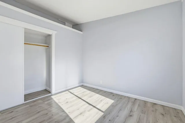 an empty room with wooden floor and closet
