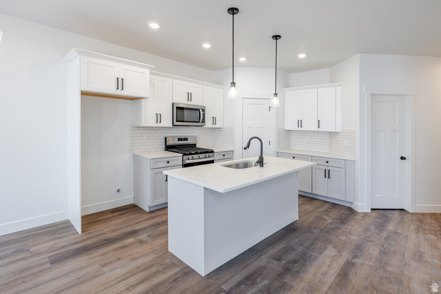 4775 Olive Avenue, Unit 412 Mapleton, UT 84664 - Photo 7 of 19 Kitchen featuring stainless steel appliances, white cabinets, hanging light fixtures, an island with sink, and dark wood-style flooring