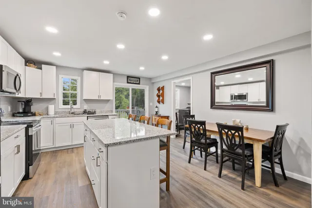 a kitchen with stainless steel appliances granite countertop white cabinets granite counter tops and a wooden floors