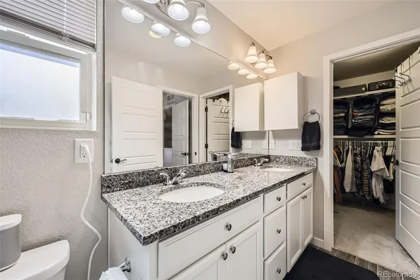 a bathroom with a granite countertop sink a toilet and a mirror