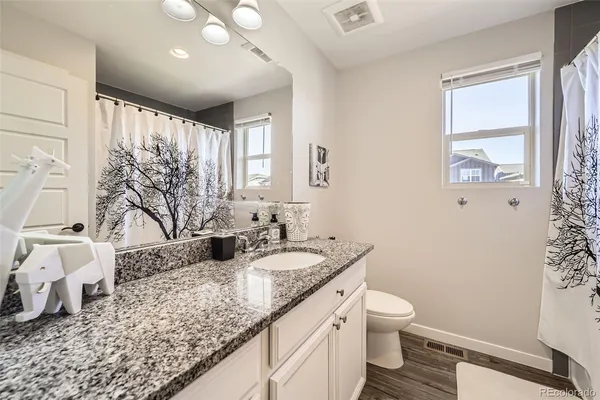 a bathroom with a granite countertop sink mirror vanity and toilet