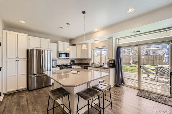 a kitchen with refrigerator a stove and a wooden floors