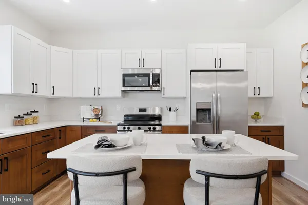 a kitchen with stainless steel appliances a table chairs microwave and refrigerator