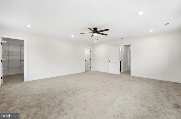 an empty room with closet and a ceiling fan