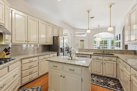 a kitchen with stainless steel appliances granite countertop a sink a stove and white cabinets