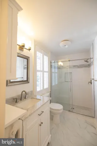 a bathroom with a granite countertop sink a toilet and shower