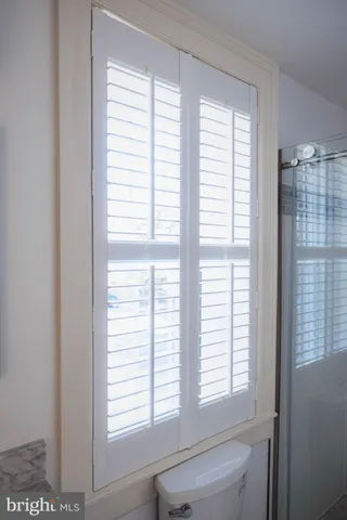 a bathroom with a window a toilet and a shower