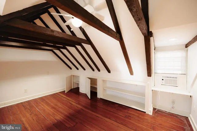 a view of an empty room with wooden floor and stairs