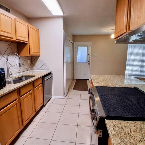 a kitchen with stainless steel appliances granite countertop a sink refrigerator and cabinets