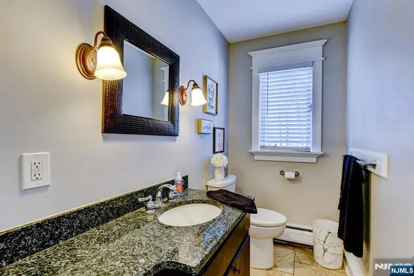a bathroom with a granite countertop sink vanity mirror and toilet